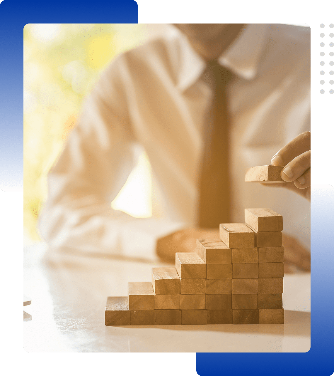 A person in business attire arranging wooden blocks in a staircase pattern.